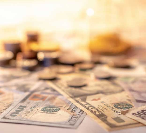 A blurred close-up of U.S. dollar bills and coins, representing financial savings and investment.