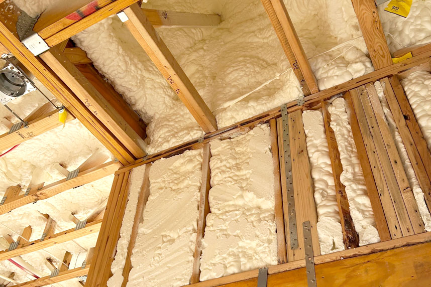 Spray foam insulation applied between ceiling joists and wall framing in residential construction project