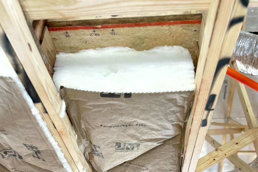 Fiberglass batt insulation fitted into a narrow framing cavity under a roof truss