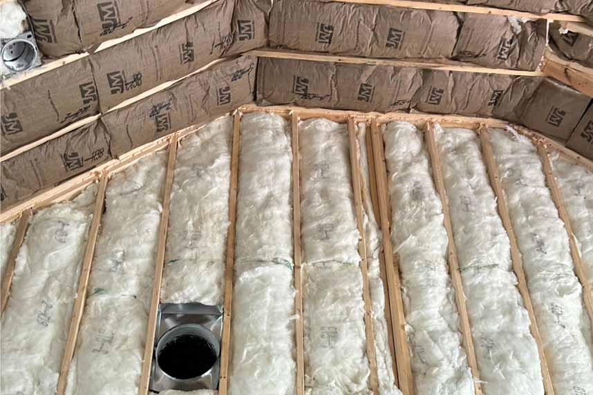 Cathedral ceiling insulated with fiberglass batts and vent duct installed, prepared by Woodman Insulation for energy-efficient performance.